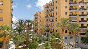 A multi-story building with balconies, surrounded by palm trees and a small water feature. - Holiday Home "Casa Roberto" with Private Balcony, Shared Pool and Wi-Fi (Candelaria)