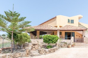 Una casa con fachada de piedra, techo de tejas y un patio cubierto.