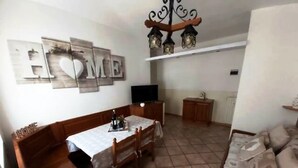 Un coin repas avec une table dressée pour quatre personnes, un canapé, un téléviseur et un lustre.