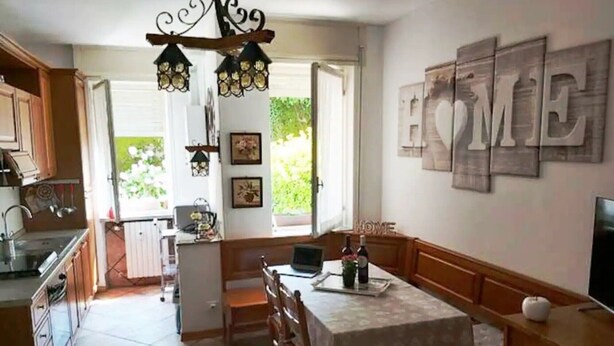 Une cuisine avec un coin repas, un lustre et un panneau décoratif portant l’inscription « HOME » au mur.