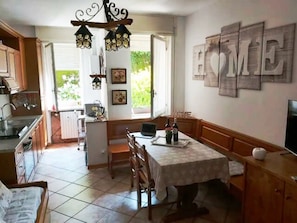 Een keuken met een eethoek, een kroonluchter en een bordje met de tekst 'HOME'.
