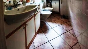 Une salle de bain avec un lavabo, des toilettes et une fenêtre.