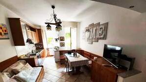 Un espace de vie compact comprenant une kitchenette, un coin repas et un téléviseur.