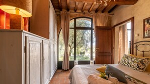 Un dormitorio con cama, armario, ventana con cortinas y candelabro.