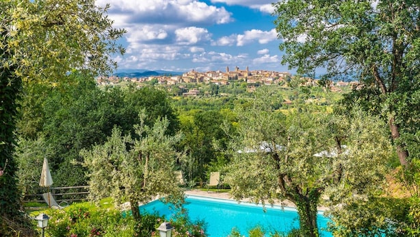 Una piscina rodeada de exuberante vegetación y una vista distante de un pueblo.