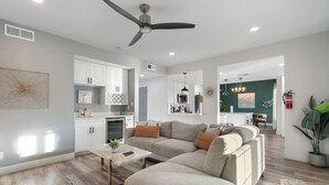 A modern living room with a sectional sofa, a coffee table, and a ceiling fan. - 5BR|Heated Pool|Pickleball| Ping Pong & Pool Table (Chandler)