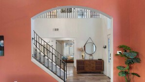 A staircase leading to an upper level, a wooden console table with a mirror, and a potted plant. - 5BR|Heated Pool|Pickleball| Ping Pong & Pool Table (Chandler)
