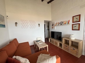 En stue med sofa, fjernsyn, lille bord og opbevaringsmøbler.