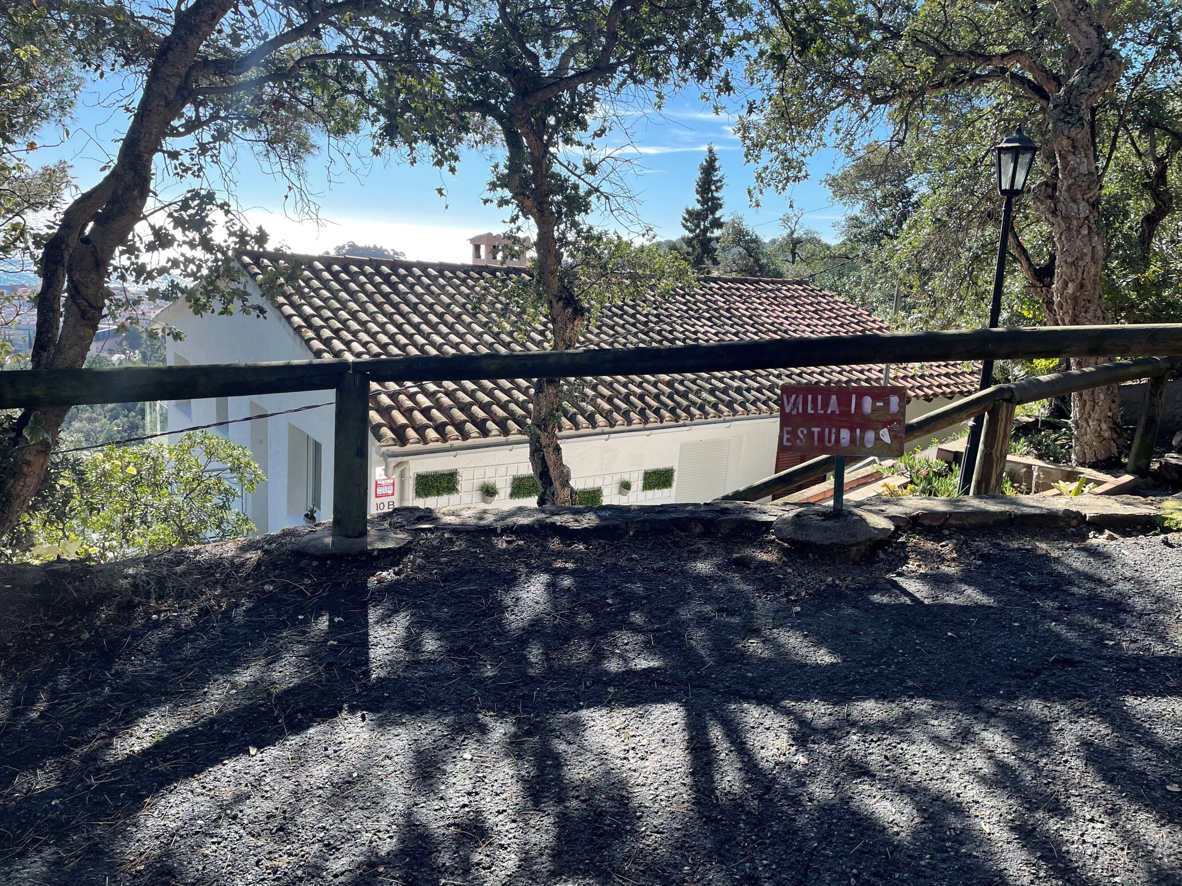 A villa with a tiled roof, surrounded by trees, and a sign indicating it is a studio.