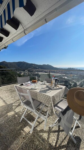 En terrasse med et morgenbord, med udsigt over by og bakkelandskab.