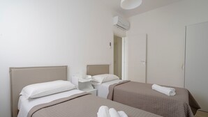 A hotel room with two beds, a bedside table with a lamp, and an air conditioning unit. - Holiday Home "Casa Kennedy" near the Beach with Balcony & Wi-Fi (monopoli)
