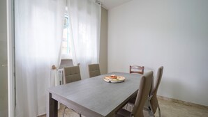 A dining area with a table, chairs, a window with curtains, and a view of the outside. - Holiday Home "Casa Kennedy" near the Beach with Balcony & Wi-Fi (monopoli)