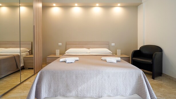 A modern hotel room with a large bed, bedside tables, a chair, and a mirror. - Holiday Home "Casa Kennedy" near the Beach with Balcony & Wi-Fi (monopoli)
