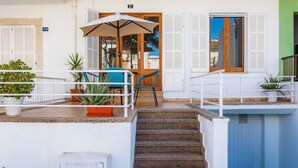 Entrada de hotel com escadaria, área de estar ao ar livre e plantas em vasos.
