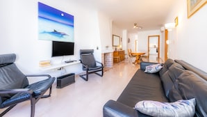 Uma sala de estar moderna com televisão de tela plana, sofás de couro preto, área de refeições e lareira.