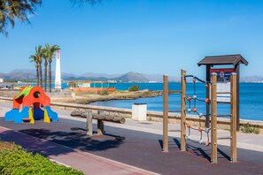 A coastal walkway with a playground, a lighthouse, and a wooden structure with information boards. - House "Can Miquel" with Wi-Fi (Can Picafort)