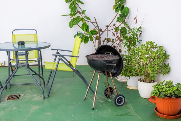 A patio with a round table, yellow chairs, a black grill, and potted plants. - House "Can Miquel" with Wi-Fi (Can Picafort)