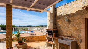 An outdoor patio with a stone barbecue, a sink, and potted plants. - Casa "Cova Dor" with Shared Pool, Garden and Wi-Fi (Santa Margalida)