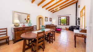 A dining area with a wooden table and chairs, a mirror, and a chandelier. - Casa "Cova Dor" with Shared Pool, Garden and Wi-Fi (Santa Margalida)