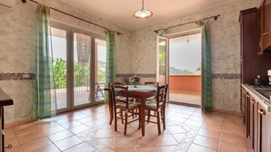 A dining area with a table and chairs, a view of the outdoors, and a kitchen area with cabinets. - Villa "Filippa" with Mountain View, Private Terrace & Private Garden (Nicosia)