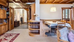 A wooden interior with a dining area, bookshelves, and a staircase.