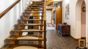 A wooden staircase with a handrail, leading to a landing with a wooden cabinet and a framed picture on the wall.