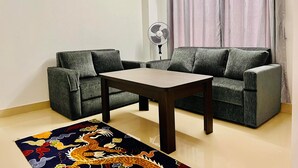 Ein Wohnzimmer mit einer Couch, einem kleinen Tisch und einem Ventilator.