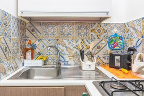 A kitchen with a sink, stove, and various utensils.