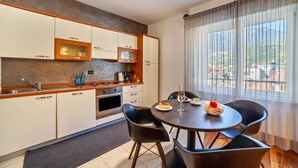 A modern kitchen with a dining area, large windows, and a view of the landscape. - Holiday Apartment 'König - The King 4th' with Balcony & Wi-Fi (Meran)