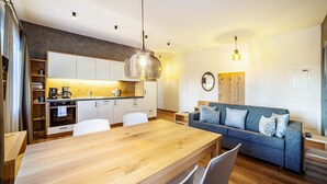 A modern kitchen with a wooden dining table, white chairs, and a built-in oven.