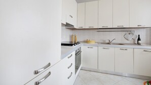 A modern kitchen with white cabinets, stainless steel appliances, and a tiled backsplash.