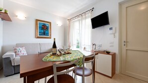 Zona pranzo con tavolo apparecchiato per due, una bottiglia di vino e due bicchieri.