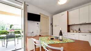 Una cucina moderna con mobili bianchi, un tavolo da pranzo in legno e un televisore montato sopra la porta.