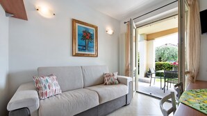 Un soggiorno con divano, un quadro, un tavolo da pranzo e vista sull'esterno.