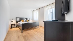 Ein Schlafzimmer mit Bett, Nachttischen, Fernseher und Kleiderschrank.