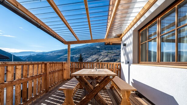 A wooden deck with a table and benches, a glass ceiling, and a mountain view. - Holiday Apartment "Binderhof Apt Obm" with Mountain View, Private Terrace and Wi-Fi (Brixen)