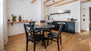 A modern kitchen with wooden beams, a dining table with chairs, and a fruit bowl. - Holiday Apartment "Binderhof Apt Obm" with Mountain View, Private Terrace and Wi-Fi (Brixen)