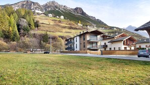 A residential area with modern houses, a church, and mountains in the background. - Apartment "Violet a due passi da Bormio" with Mountain View, Private Balcony & Wi-Fi (Valdidentro)