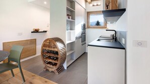 A compact kitchen with built-in appliances, a wine rack, and a window with a view. - Apartment "Violet a due passi da Bormio" with Mountain View, Private Balcony & Wi-Fi (Valdidentro)