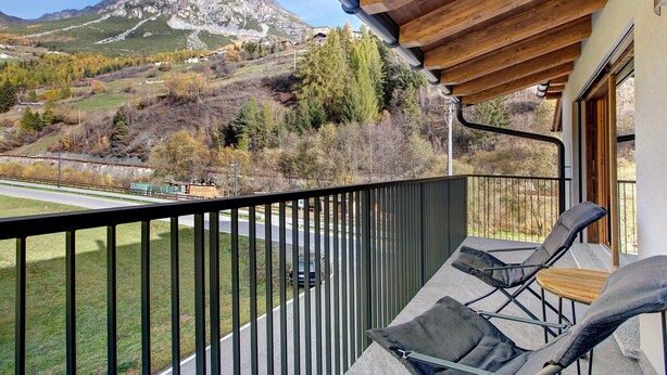 A balcony with a view of a mountainous landscape, a road, and a parked car. - Apartment "Violet a due passi da Bormio" with Mountain View, Private Balcony & Wi-Fi (Valdidentro)
