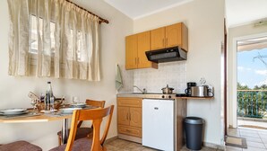 A compact kitchen with wooden cabinets, a white refrigerator, and a dining area with chairs and a table set for two.