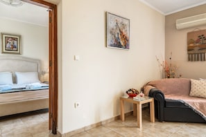 Une pièce comprenant un lit, un canapé, une petite table avec un vase et un tableau accroché au mur.