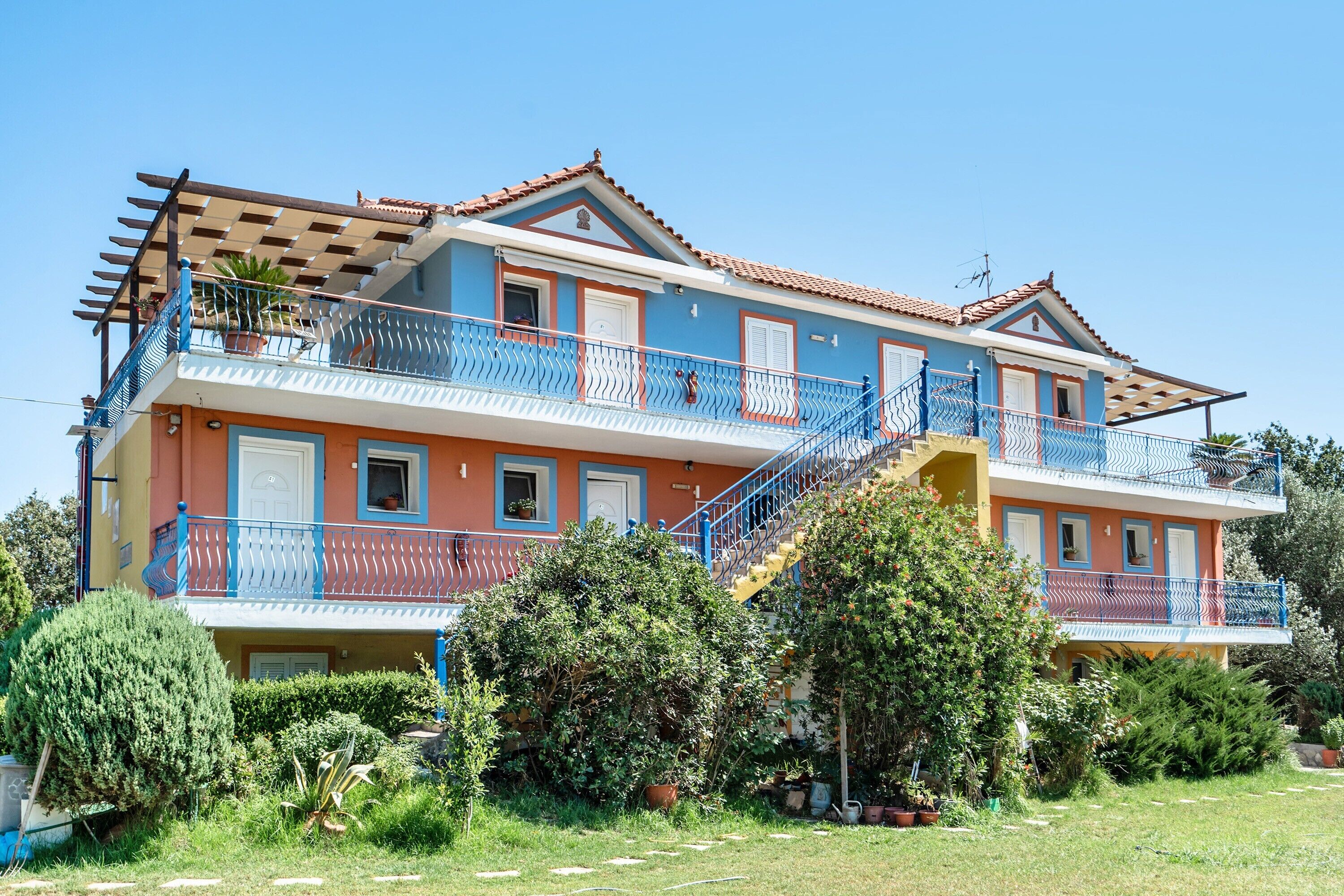 Un edificio de varios pisos con balcones, una escalera y un jardín.