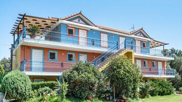 Un edificio de varios pisos con balcones, una escalera y un jardín.