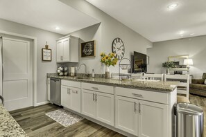 Eine moderne Küche mit weißen Schränken, Granit-Arbeitsplatten und einem eingebauten Geschirrspüler.