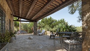 A covered outdoor area with stone flooring, a car parked nearby, and outdoor furniture including a bench and chairs. - Casa Degli Ulivi with sea view, Wi-Fi, and pet-friendly accommodation (Collesano)