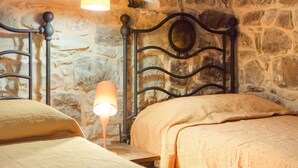 A room with two beds, a stone wall, and a hanging light fixture. - Casa Degli Ulivi with sea view, Wi-Fi, and pet-friendly accommodation (Collesano)