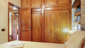 A bedroom with a bed, a wooden wardrobe, and a stone wall. - Casa Degli Ulivi with sea view, Wi-Fi, and pet-friendly accommodation (Collesano)