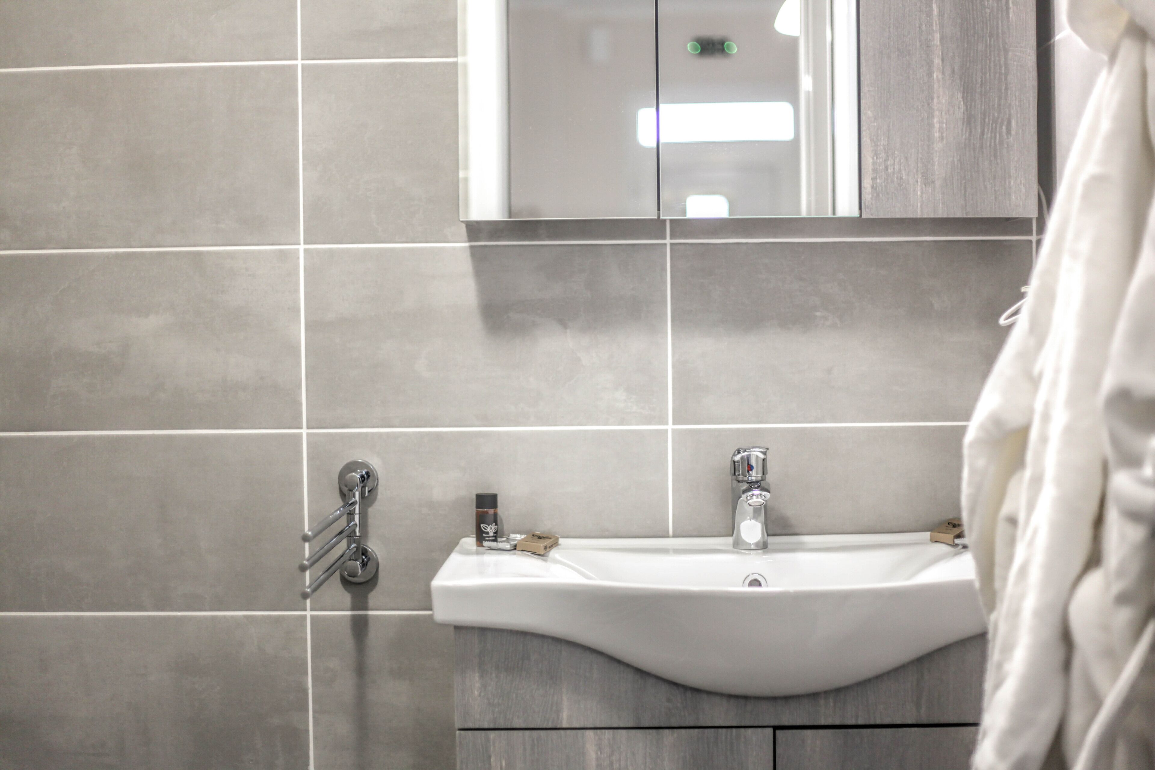 A bathroom with a white sink, a mirror, and a towel rack.