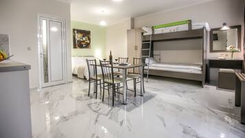 A modern hotel room with a marble floor, a bunk bed, a dining table with chairs, and a small desk with a mirror.
